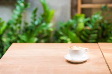 Ahşap masada beyaz fincan latte sanat doku kahve