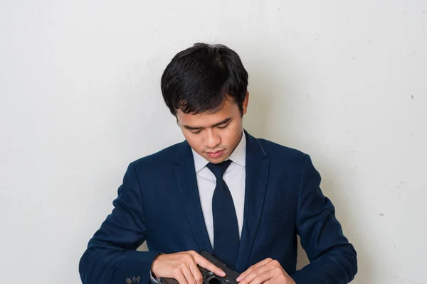 Hombre de negocios en traje sosteniendo pistola de mano sobre fondo blanco —  Fotos de Stock