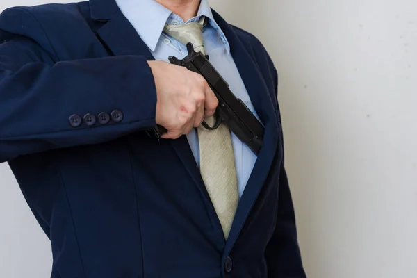 Hombre de negocios en traje sosteniendo pistola de mano sobre fondo blanco —  Fotos de Stock