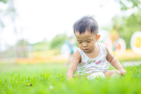 Yeşil park alanında oturan sevimli küçük çocuk — Stok fotoğraf