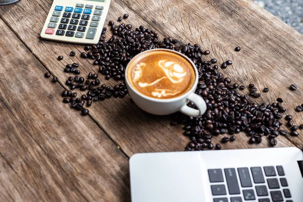 Latte art tazza di caffè e chicco di caffè con computer portatile su woo — Foto Stock