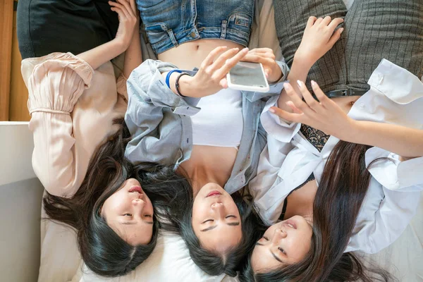 Női barát csoport használata okostelefon fekve ágyon — Stock Fotó