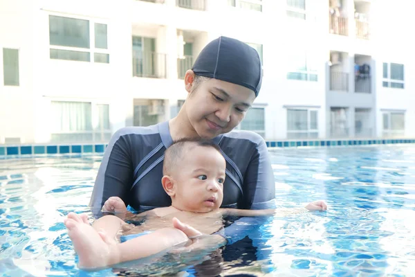 Mother trainning baby pojke simning i poolen — Stockfoto