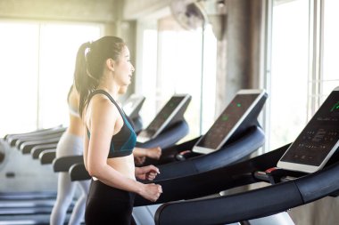 Fitness salonunda koşu bandı üzerinde çalışan kadın grubu