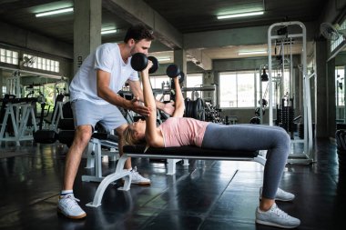 Spor salonunda antrenörle antrenman yapan beyaz kadınlar.