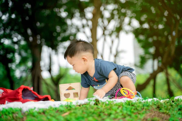 Leksakspojken sitter i stadens gröna park och leker leksak — Stockfoto