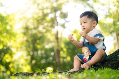 Bebek oğlan yeşil çayır şehir parkında oynuyor.