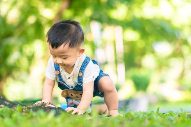 Şehir parkında yeşil çimlerde sürünen komik çocuk.