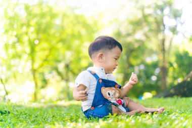 Çocuk çocuk ağacın altında çimlerle eğleniyor.