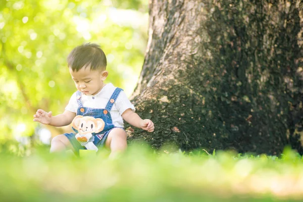 Bebek oğlan yeşil çayır şehir parkında oynuyor. — Stok fotoğraf