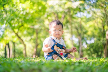 Çocuk çocuk ağacın altında çimlerle eğleniyor.