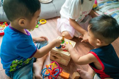 Asyalı çocuk ve kız odada birlikte tahta oyuncağı oynamanın tadını çıkarıyorlar.