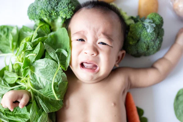 Baby unge pojke liggande gråta med olika grönsaker — Stockfoto