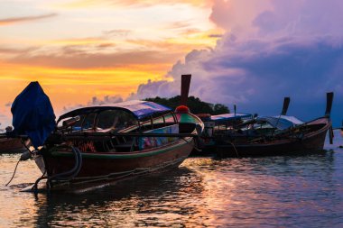 Deniz sahilinde, siluet ahşap kayıkla renkli günbatımı gökyüzü