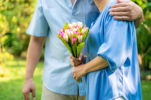 Middle aged couple hold flower together ingreen park