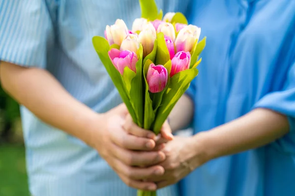 Middle aged couple hold flower together ingreen park