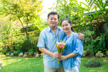 Orta yaşlı çift çiçekleri bir arada tutar.