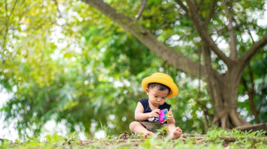 Sarı şapkalı çocuk yeşil şehir parkında seyahat ediyor.