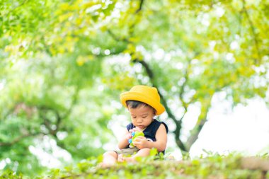Sarı şapkalı çocuk yeşil şehir parkında seyahat ediyor.