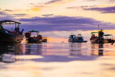 Deniz sahilinde gün batımı silueti. Bulutlu renkli gökyüzü.