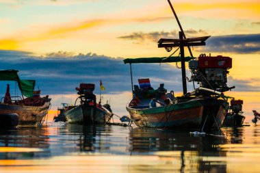 Deniz sahilinde gün batımı silueti. Bulutlu renkli gökyüzü.