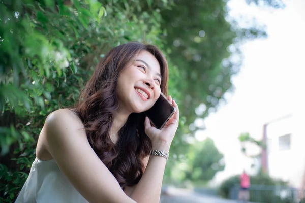 美丽的微笑的女人在城市免费公园的晨光中使用智能手机 — 图库照片