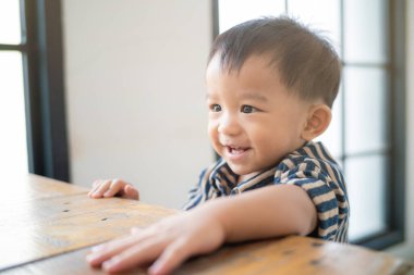Sevimli, komik çocuk oturma odasında tahta kutuyla ayakta durmaya çalış.