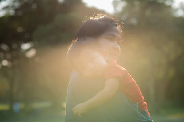 Asian mom carry baby boy in city park sunset light energy of life concept