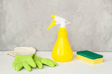 Cam spreyi, sünger ve eldivenler gri arka planda, bahar temizliği konsepti. Deterjan ve temizlik aksesuarları. Küçük işletme fikri