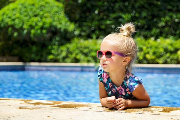 Menina feliz na piscina ao ar livre no dia quente de verão. As crianças aprendem a nadar. As crianças brincam em resort tropical. Família praia férias . — Fotografia de Stock