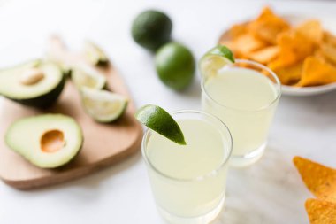 Taze avokado, kireç, içecek ve mermer arka plan üzerinde yatan nacho cips. Cinco de Mayo parti tarifi