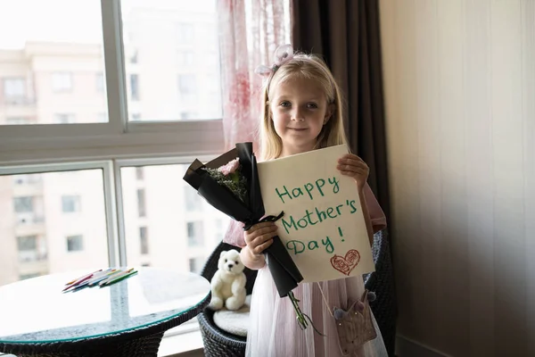 Kleine dochter Holding geschilderde briefkaart en boeket van bloemen voor mam. Gelukkig Mother Day concept — Stockfoto