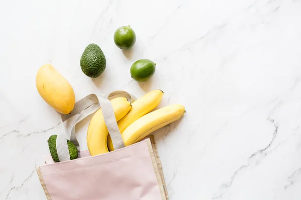 Top View roze tas van verschillende verse gezondheid voedsel liggend op witte marmeren achtergrond. Kopieer ruimte. Platte lag. Minimale herbruikbare afval concept — Stockfoto