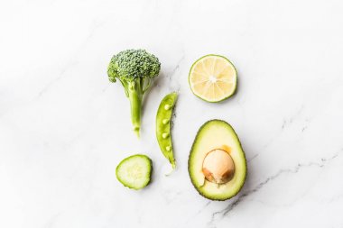 Taze avokado, limon, brokoli, bezelye, salatalık, yeşil biber. Düz yatıyordu. Gıda konsepti. Beyaz mermer arka plan üzerinde yatan yeşil sebzeler