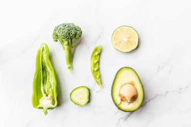 Taze avokado, limon, brokoli, bezelye, salatalık, yeşil biber. Düz yatıyordu. Gıda konsepti. Beyaz mermer arka plan üzerinde yatan yeşil sebzeler