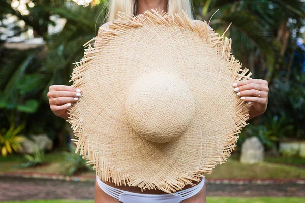 Крупный план портрет молодой женщины, держащей большую соломенную шляпу, красивая женщина, наслаждающаяся тропической солнечной погодой — стоковое фото