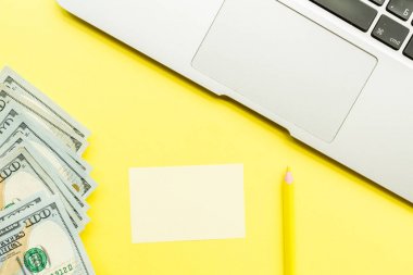 Sarı arka plan üzerinde dizüstü bilgisayar ve nakit para ile Mockup Boş sayfa. Metni girebetmek için kopyalama alanı ile üstteki görünüm. Düz yatıyordu, iş konsepti