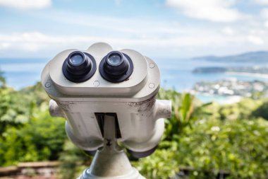 Bozuk para çalışan binoküler Görüntüleyici Phuket su kenarında sahil şeridine bakıyor. Güzel bulutlu gökyüzü ve deniz ile peyzaj