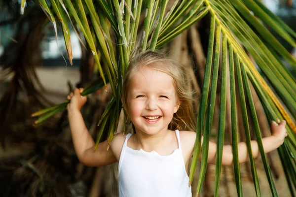 Retrato de niña feliz con hoja de palma. Concepto de vacaciones de verano, vibraciones tropicales. Niño sonriendo . — Foto de Stock