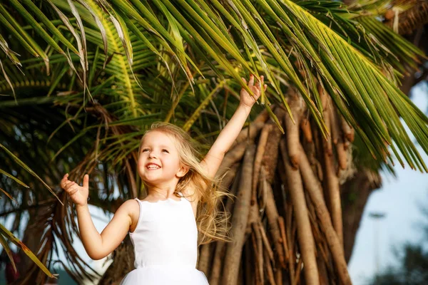 Retrato de menina feliz com folha de palmeira. Conceito de férias de verão, vibrações tropicais. Miúdo a sorrir . — Fotografia de Stock