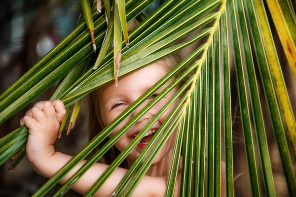 Retrato de niña feliz con hoja de palma. Concepto de vacaciones de verano, vibraciones tropicales. Niño sonriendo . — Foto de Stock
