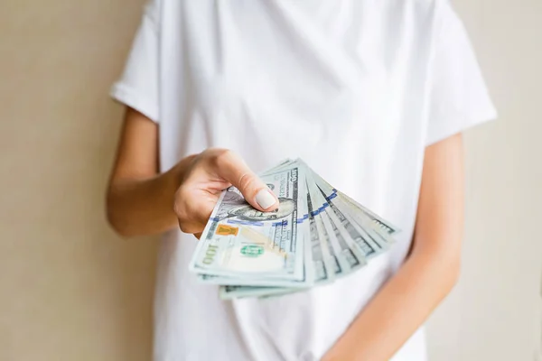 Kobieta trzyma gotówki 100 dolarów rachunki na beżowy tle. Koncepcja biznesowa i finansowa — Zdjęcie stockowe