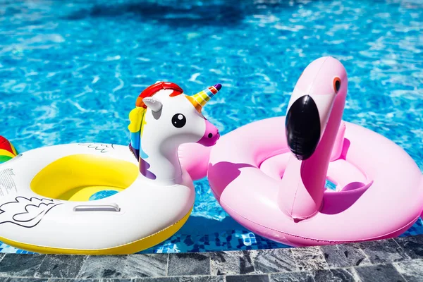 Unicórnio branco colorido inflável e flamingo rosa na piscina. Hora de verão na piscina com brinquedos de plástico. Relaxamento e conceito divertido — Fotografia de Stock