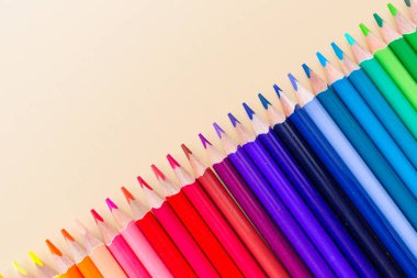 Pastel turuncu kağıt üzerinde yatan birçok boya kalemleri ile parlak ve renkli arka plan. Üst görünüm, düz yatıyordu, mockup, havai, kopyalama alanı. Eğitim ve okul kavramına geri dönüş