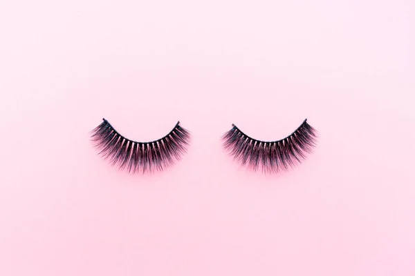 False eyelashes lying on pink background. Beauty and makeup concept. Flatlay, mockup, overhead, top view copy space — Stock Photo, Image