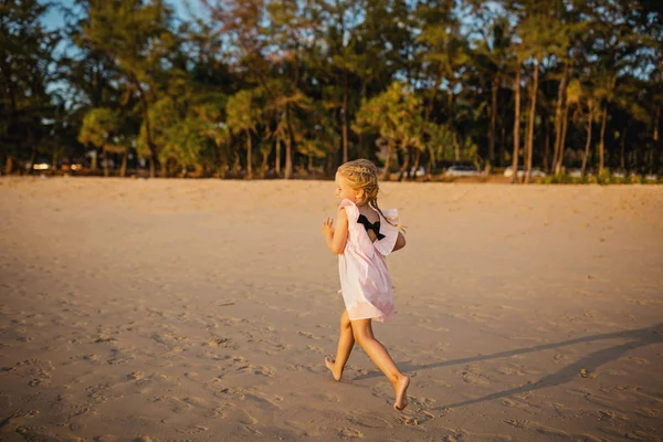 Menina bonito correndo na praia. Hora do pôr-do-sol. Criança se divertindo em férias de férias com luz solar de volta - Juventude, estilo de vida, viagem e conceito de felicidade — Fotografia de Stock