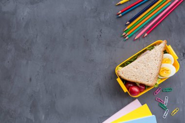 Okul malzemeleri ve sandviç ve sebze ile öğle yemeği kutusu. Okula dönüyoruz. Sağlıklı beslenme alışkanlıkları kavramı-ücretsiz metin alanı ile arka plan düzeni. Düz yatıyordu kompozisyon, mockup, üst görünüm