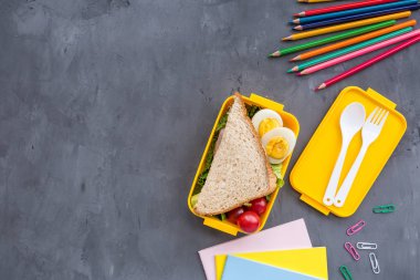 Okul malzemeleri ve sandviç ve sebze ile öğle yemeği kutusu. Okula dönüyoruz. Sağlıklı beslenme alışkanlıkları kavramı-ücretsiz metin alanı ile arka plan düzeni. Düz yatıyordu kompozisyon, mockup, üst görünüm