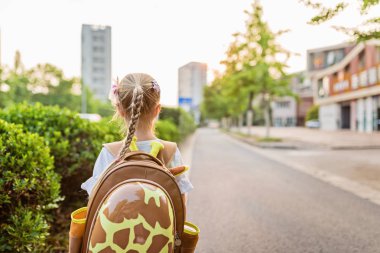 Okul çantası, okul öncesi ve anaokulu eğitim kavramı ile tek başına eğitim okulu öğrendikten sonra geri eve yürürken arkasında çocuk kız öğrenci. Sonbaharda ilk gün