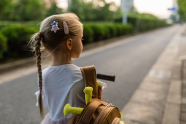 Okul çantası, okul öncesi ve anaokulu eğitim kavramı ile tek başına eğitim okulu öğrendikten sonra geri eve yürürken arkasında çocuk kız öğrenci. Sonbaharda ilk gün